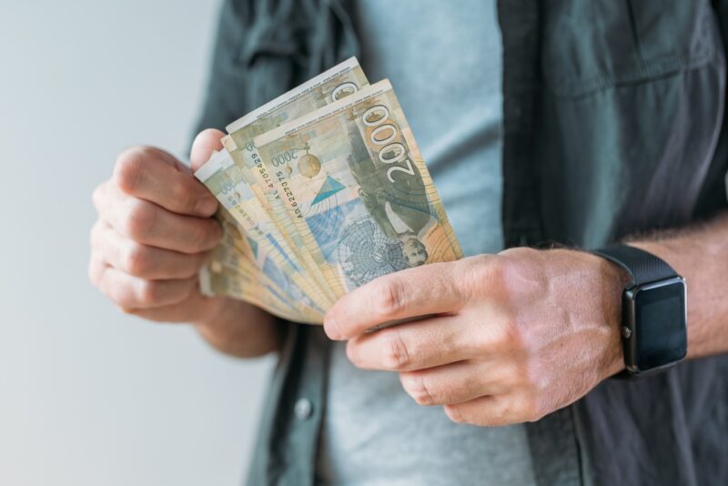 Osoba drži novac u rukama kao simbol planiranja budžeta za reklamni materijal i marketing kampanju